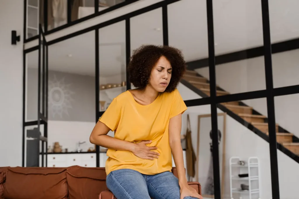 Mulher com a mão no abdome precisando de tratamentos para diástase abdominal