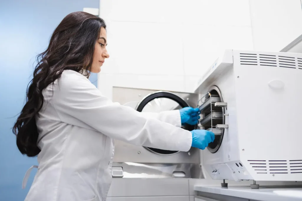 Assistente feminina tirando bolsos com instrumentos odontológicos esterilizados para demonstrar o que é autoclave