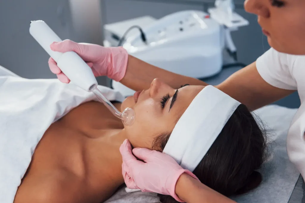 Mulher deitada em clínica de estética recebendo limpeza de pele com alta frequência