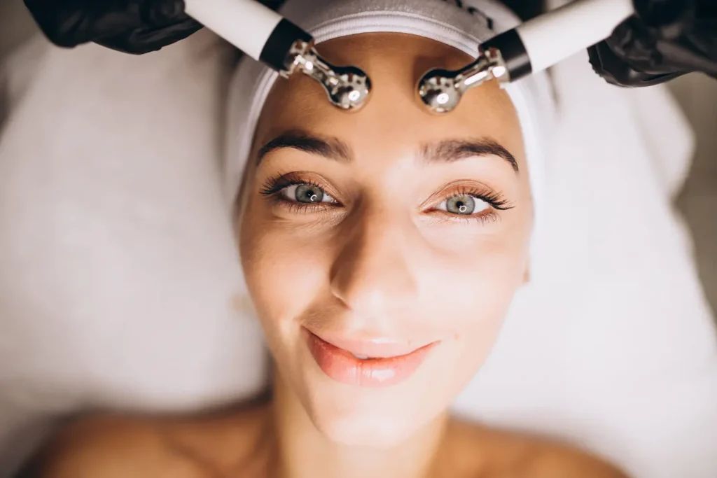 Mulher sorrindo enquanto faz tratamento de microcorrentes em uma clínica de estética