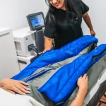 Esteticista preparando paciente para tratamento de pressoterapia em clínica de estética.